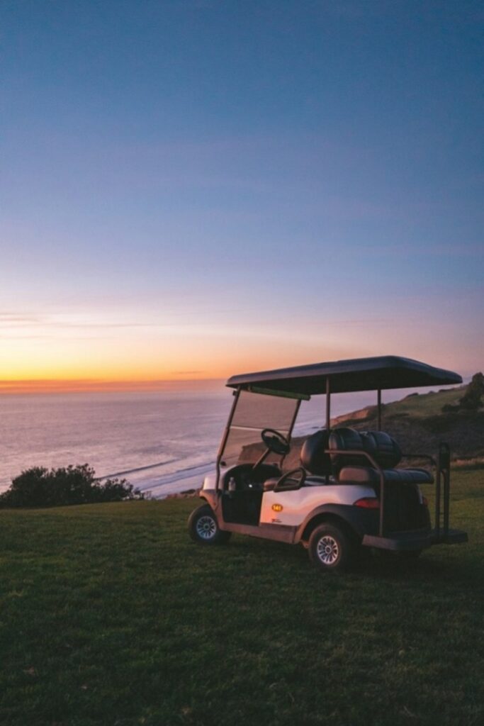 A golf cart parked near the sea at sunset time